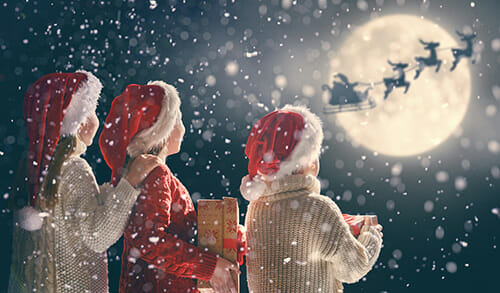 two children looking at Father Christmas in the sky